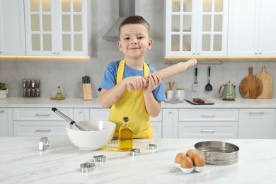 Photo of Little helper. Cute boy making dough for cookies in kitchen at home