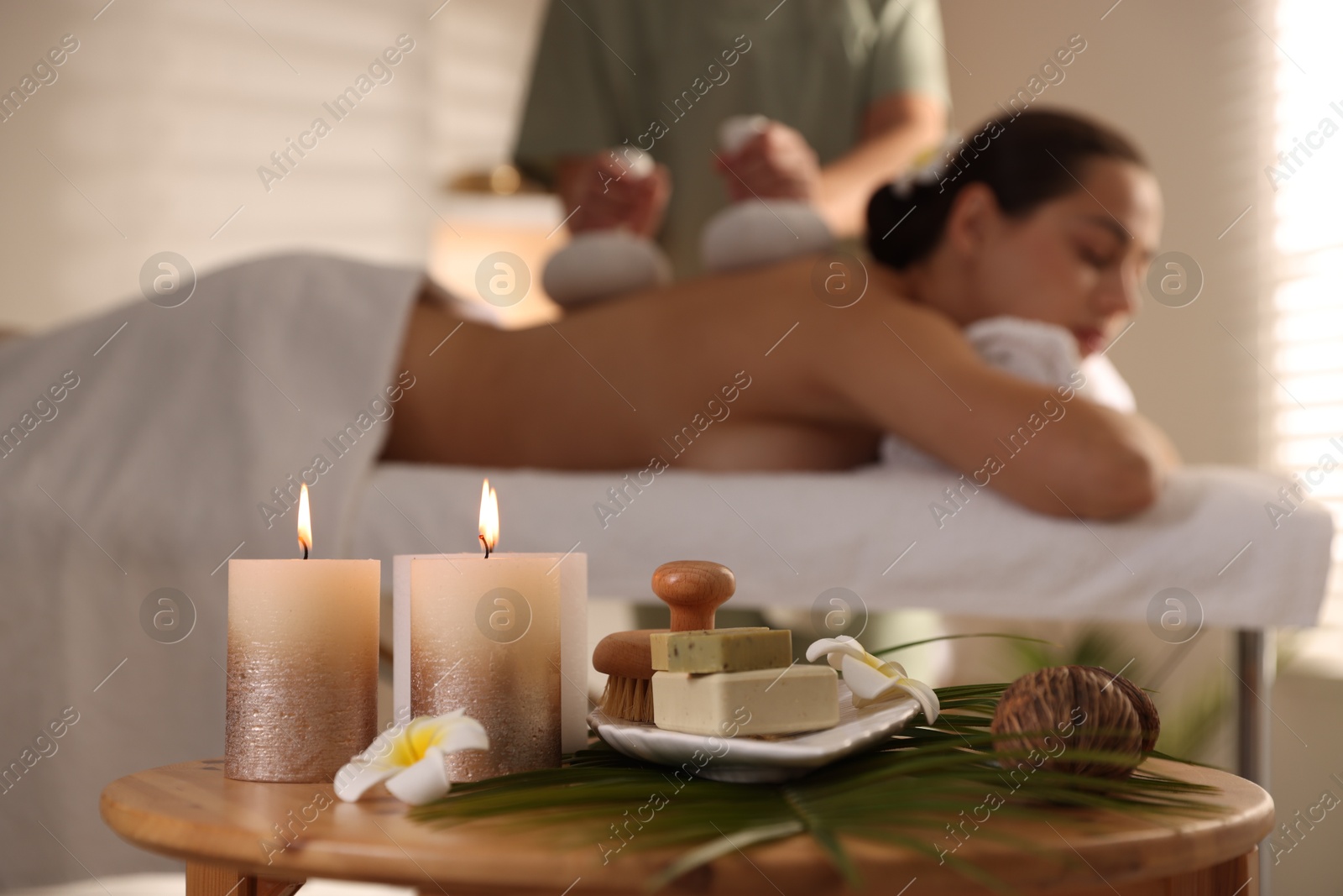 Photo of Woman receiving back massage with herbal bags in salon, focus on spa supplies