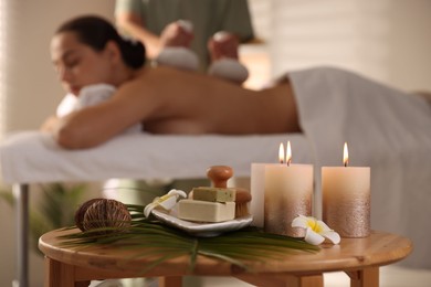 Photo of Woman receiving back massage with herbal bags in salon, focus on spa supplies