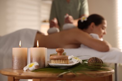 Photo of Woman receiving back massage with herbal bags in salon, focus on spa supplies