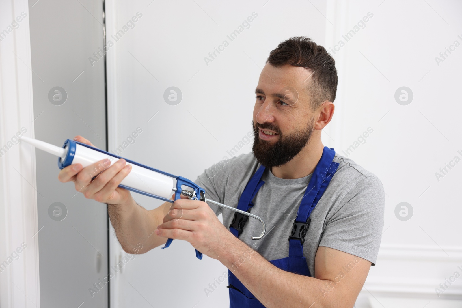 Photo of Worker with caulking gun sealing window indoors