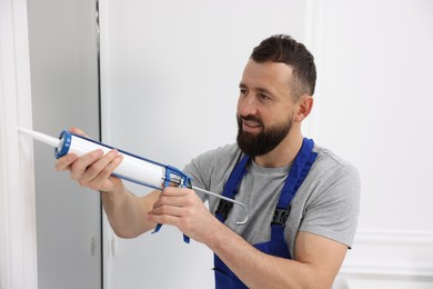 Photo of Worker with caulking gun sealing window indoors