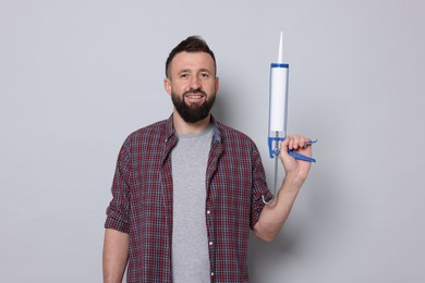 Photo of Man with caulking gun on gray background