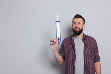 Photo of Man with caulking gun on gray background, space for text