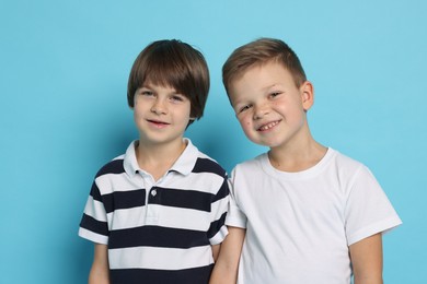 Photo of Portrait of cute brothers on light blue background