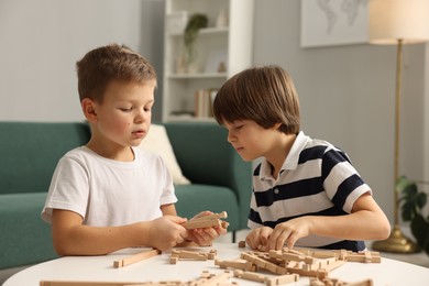 Photo of Cute brothers playing with wooden construction set at table indoors