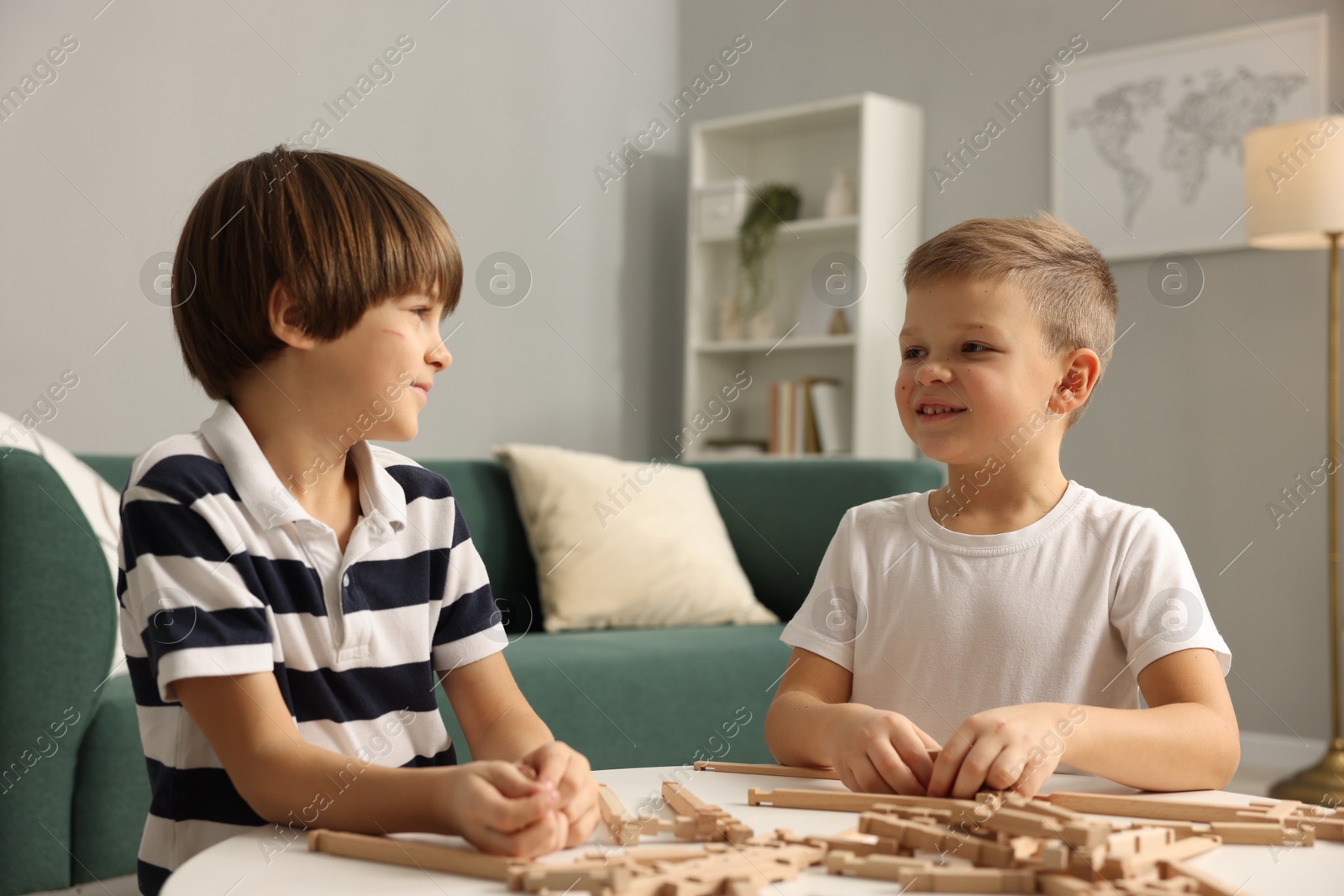 Photo of Cute brothers playing with wooden construction set at table indoors