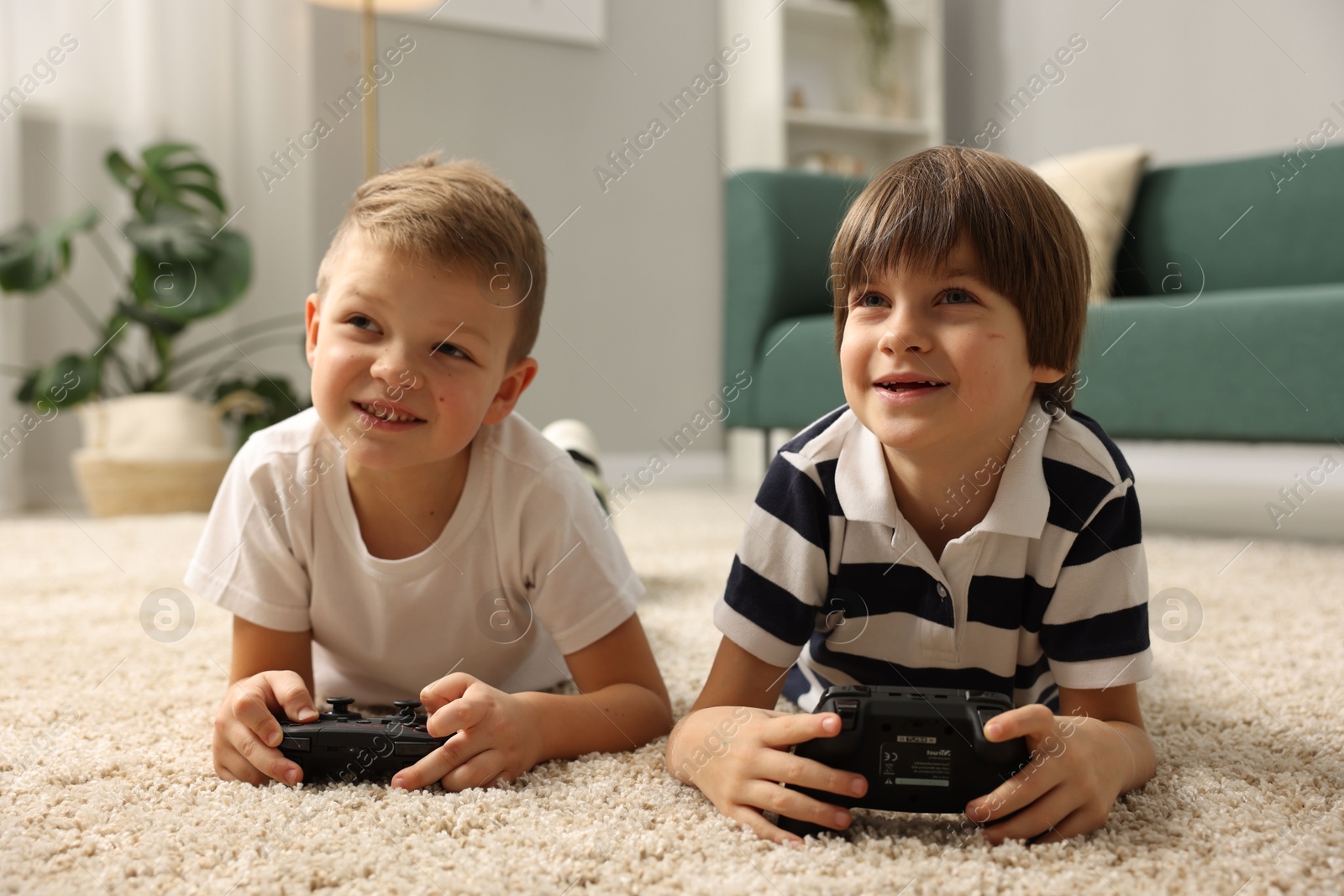 Photo of Cute brothers playing video game on floor at home