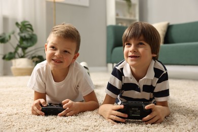 Photo of Cute brothers playing video game on floor at home