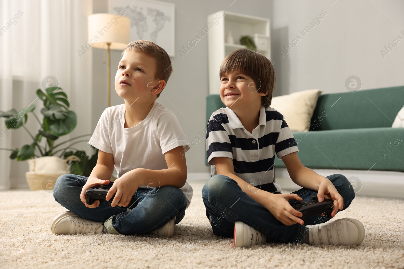 Photo of Cute brothers playing video game on floor at home