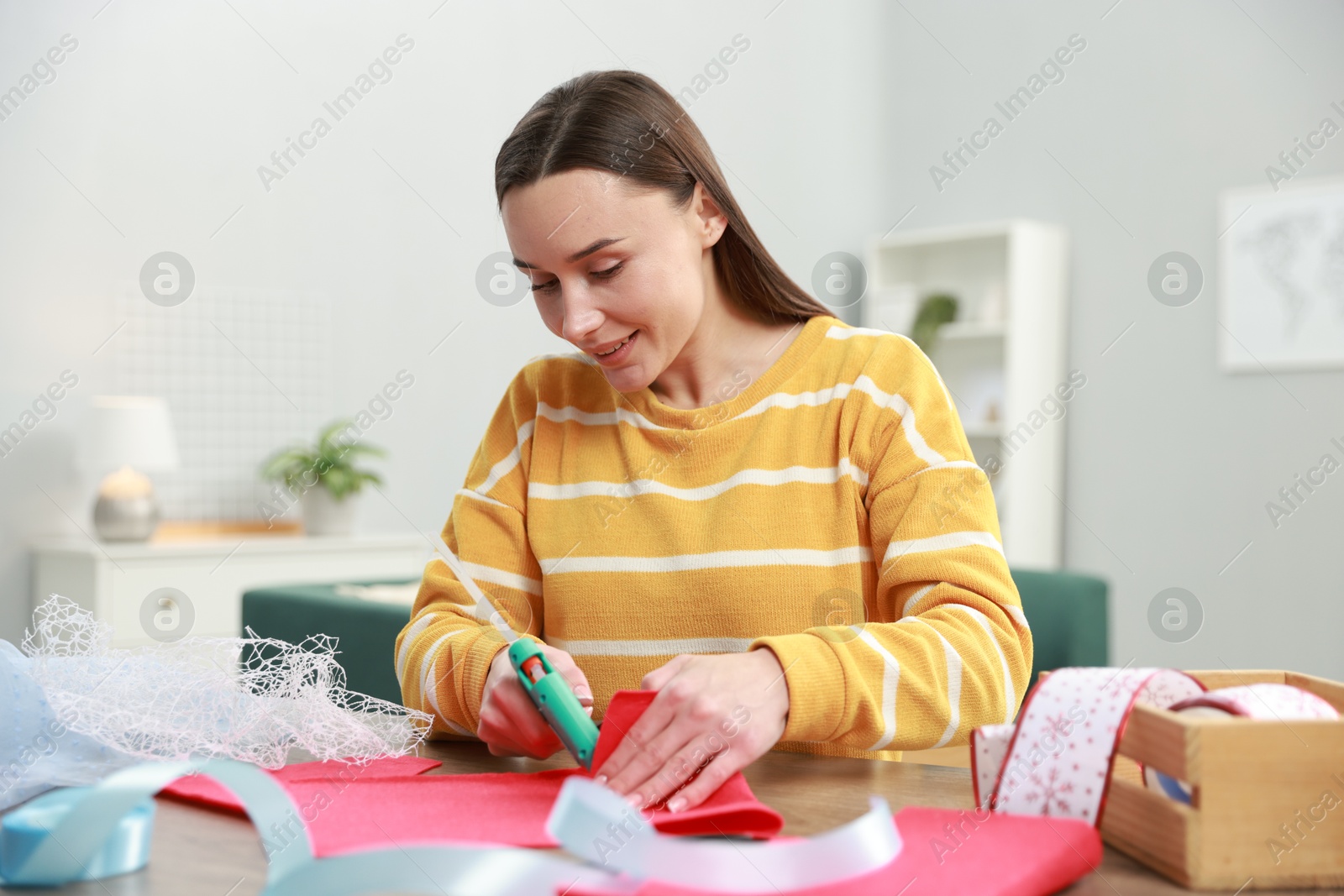 Photo of Woman with hot glue gun making craft at table indoors