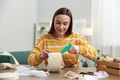 Photo of Woman with hot glue gun making craft at table indoors