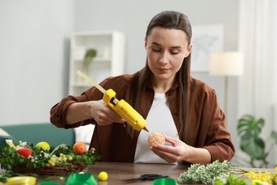 Photo of Woman with hot glue gun making craft at table indoors