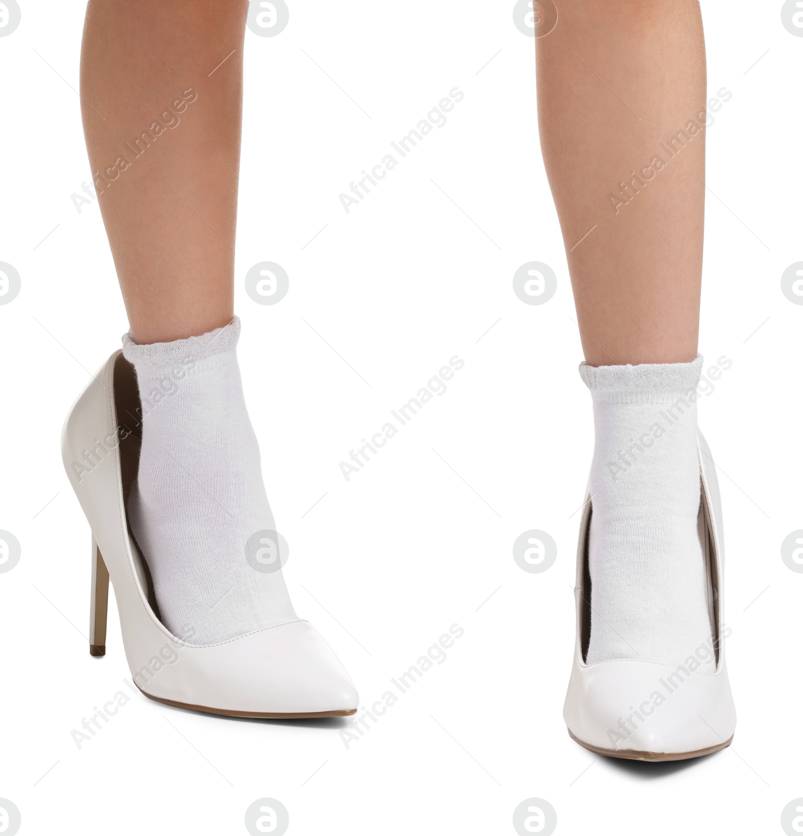 Photo of Little girl wearing oversized high heeled shoes on white background, closeup