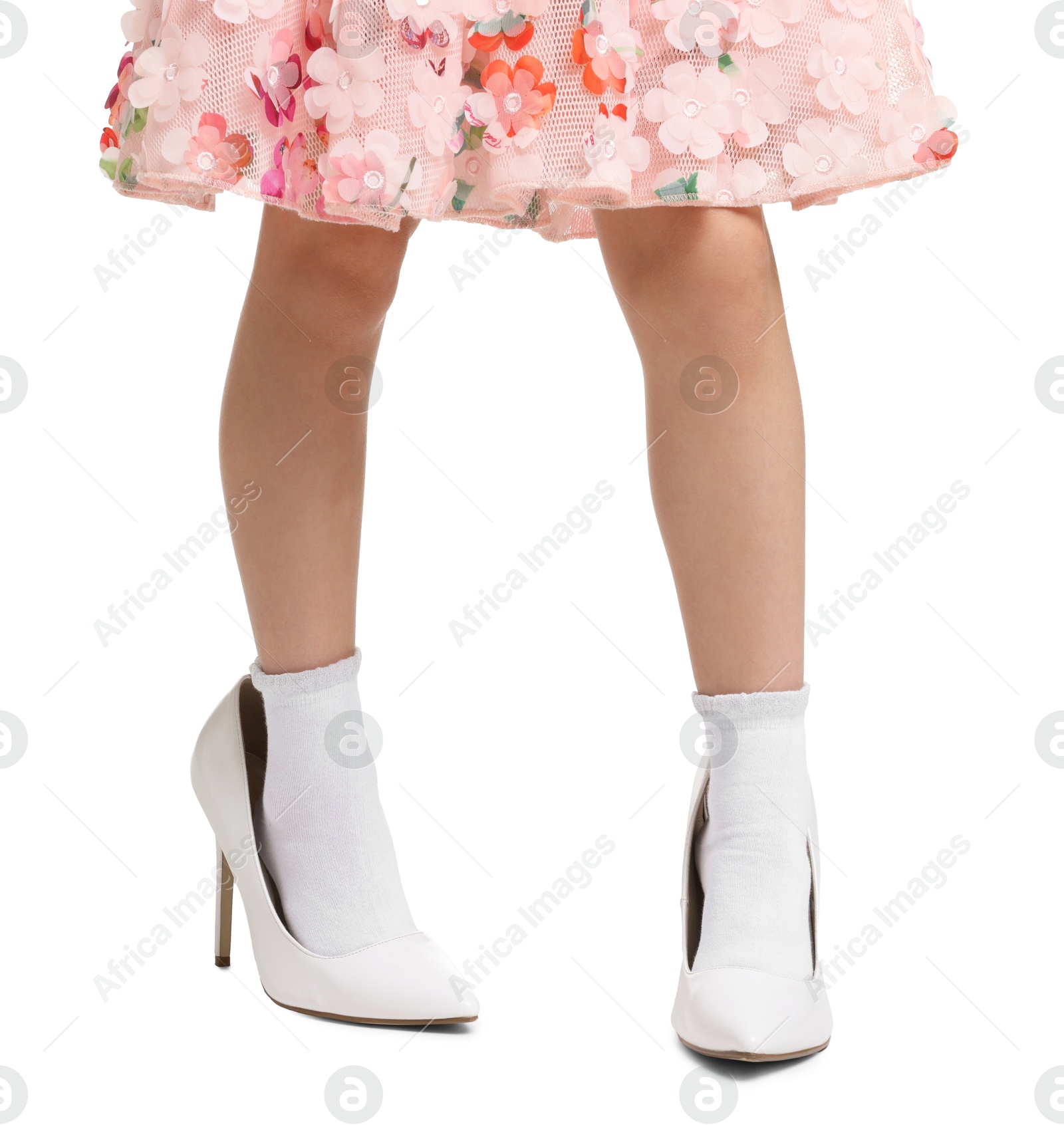 Photo of Little girl wearing oversized high heeled shoes on white background, closeup