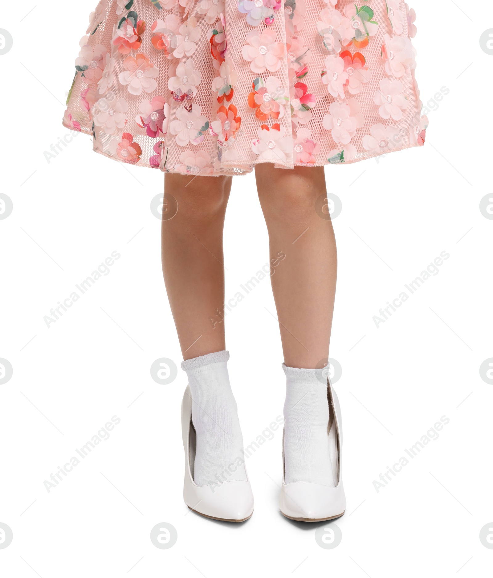 Photo of Little girl wearing oversized high heeled shoes on white background, closeup