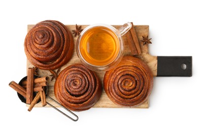 Photo of Delicious cinnamon roll buns with tea and spices isolated on white, top view