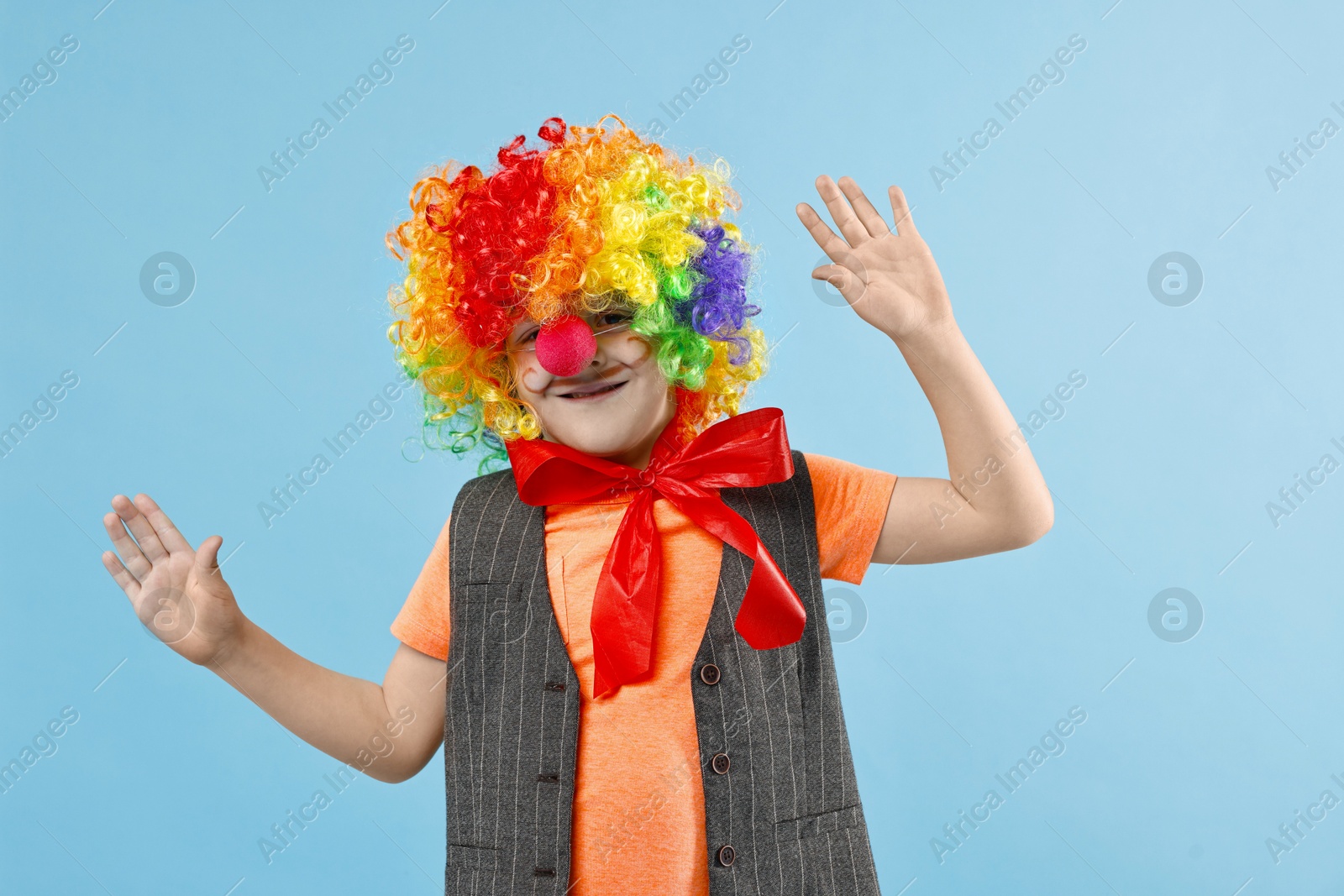 Photo of Happy boy dressed like clown on light blue background. Surprise party