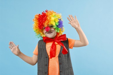 Photo of Happy boy dressed like clown on light blue background. Surprise party