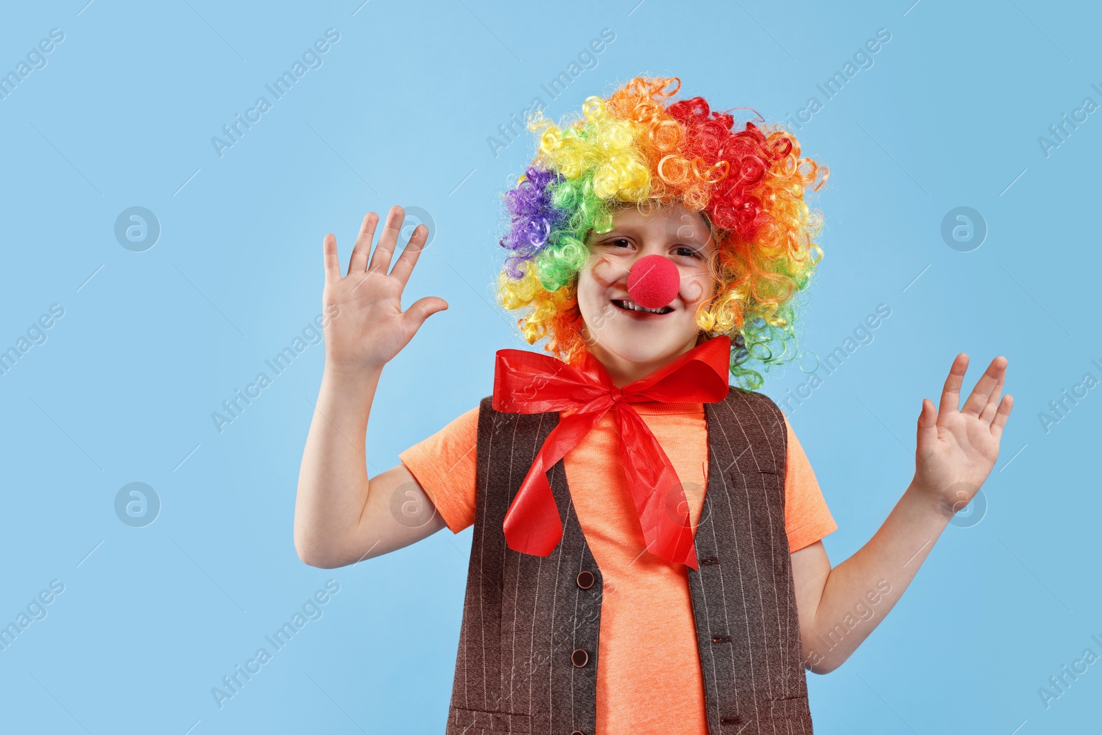 Photo of Happy boy dressed like clown on light blue background. Surprise party