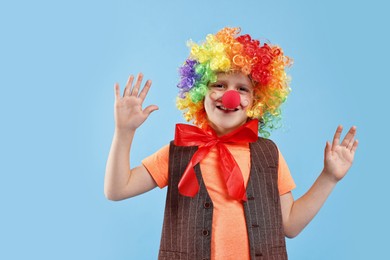 Photo of Happy boy dressed like clown on light blue background. Surprise party