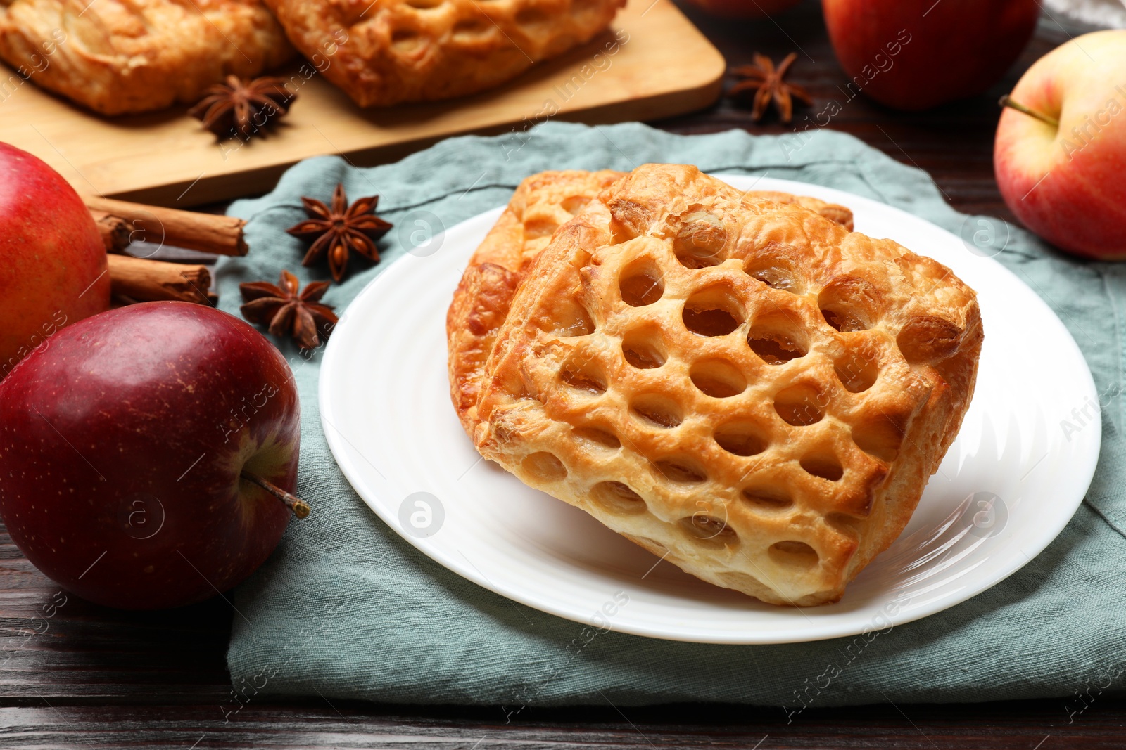 Photo of Delicious puff pastries, apples, cinnamon and anise stars on wooden table, closeup