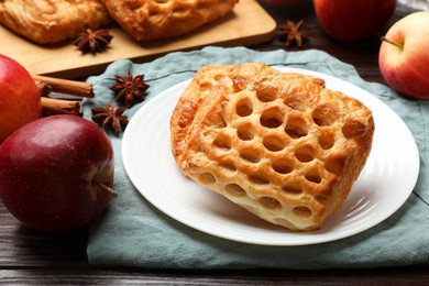 Photo of Delicious puff pastries, apples, cinnamon and anise stars on wooden table, closeup