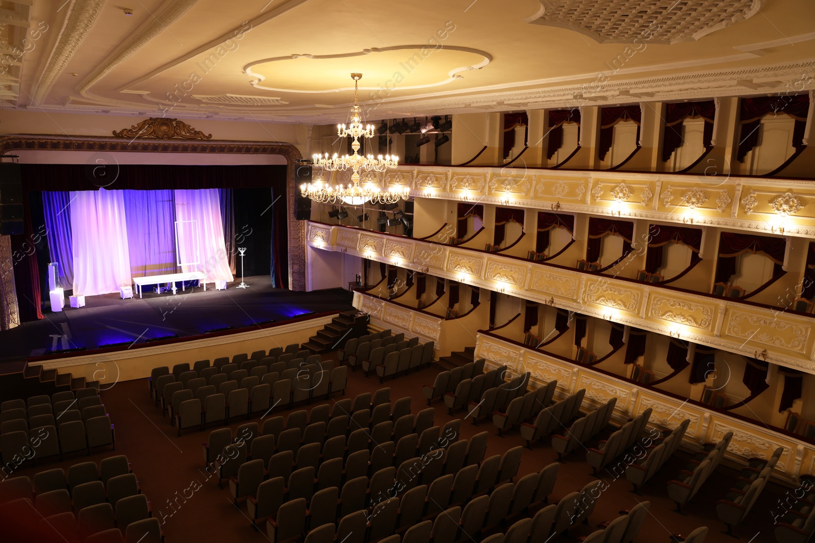 Photo of Theatre interior with stage, rows of comfortable seats and beautiful chandelier