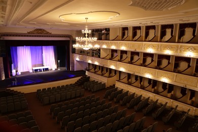 Photo of Theatre interior with stage, rows of comfortable seats and beautiful chandelier