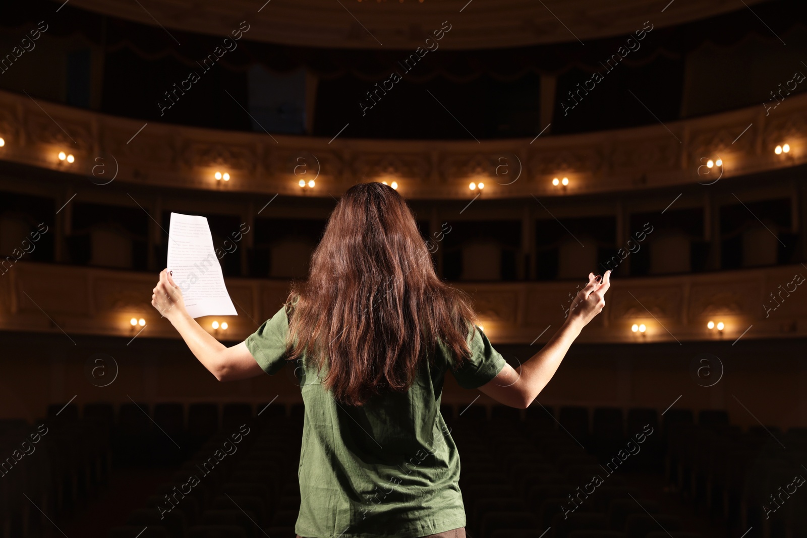 Photo of Professional actress rehearsing on stage in theatre, back view