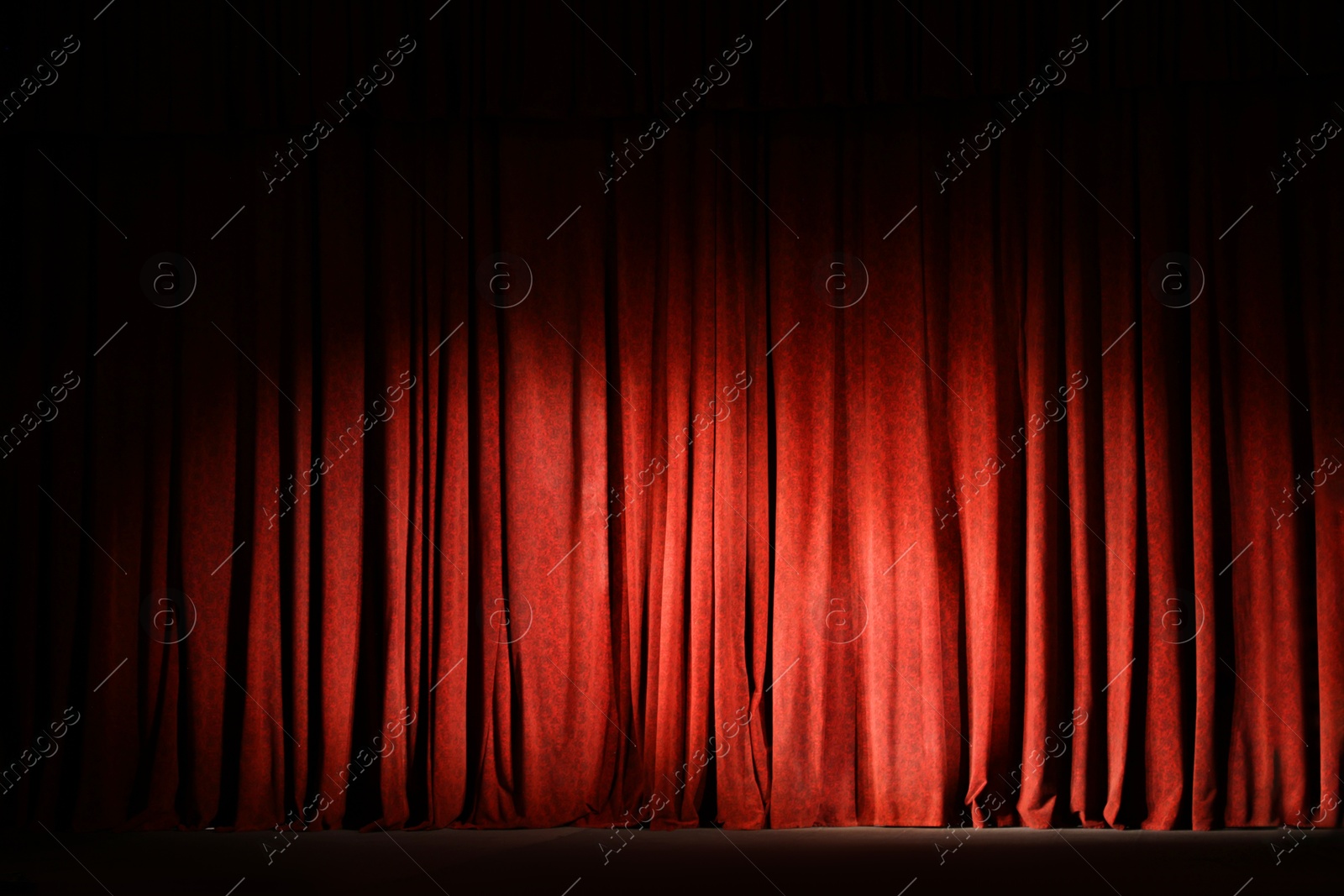 Photo of Elegant closed red curtains illuminated by spotlight in theatre