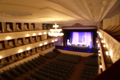 Photo of Blurred view of theatre interior with stage, comfortable seats and beautiful chandelier