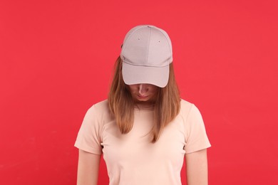 Photo of Woman in stylish baseball cap on red background. Mockup for design