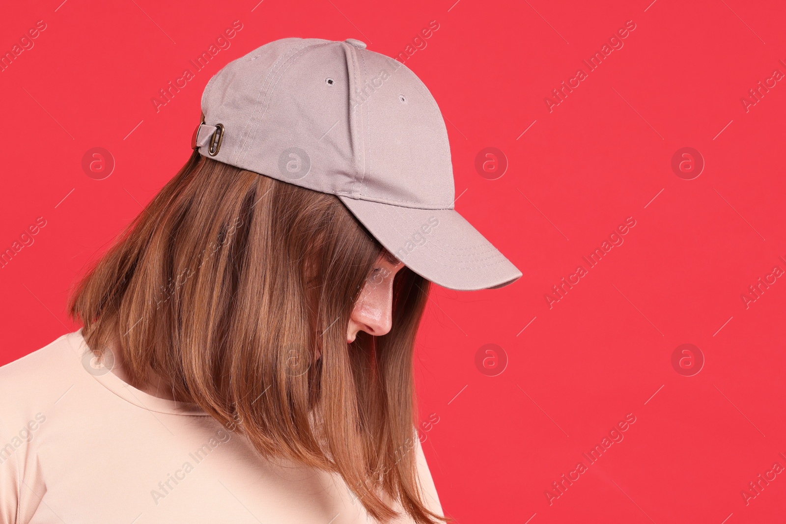 Photo of Woman in stylish baseball cap on red background. Mockup for design