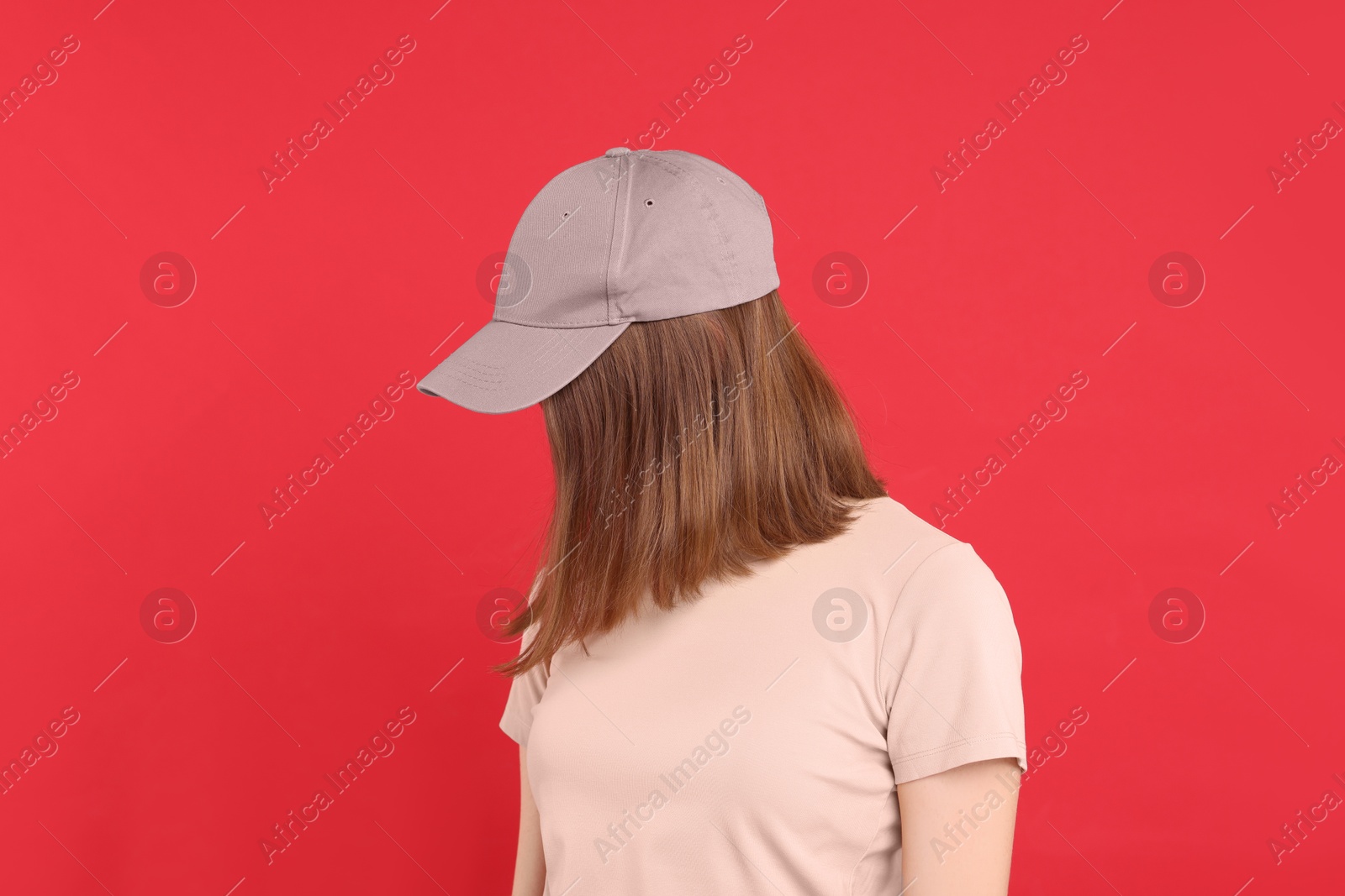 Photo of Woman in stylish baseball cap on red background. Mockup for design