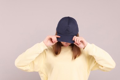 Woman in stylish baseball cap on grey background. Mockup for design