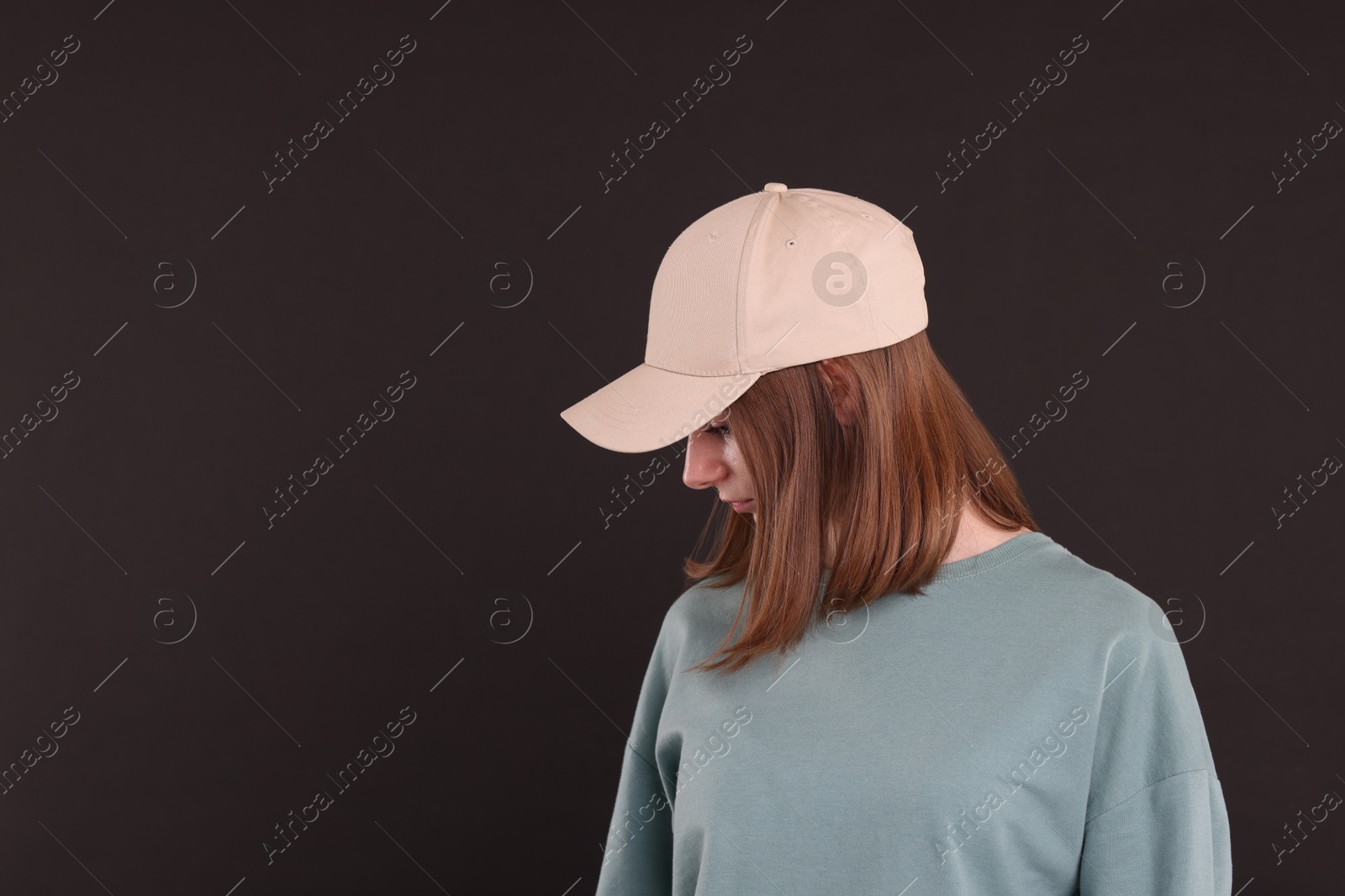 Photo of Woman in stylish baseball cap on black background. Mockup for design