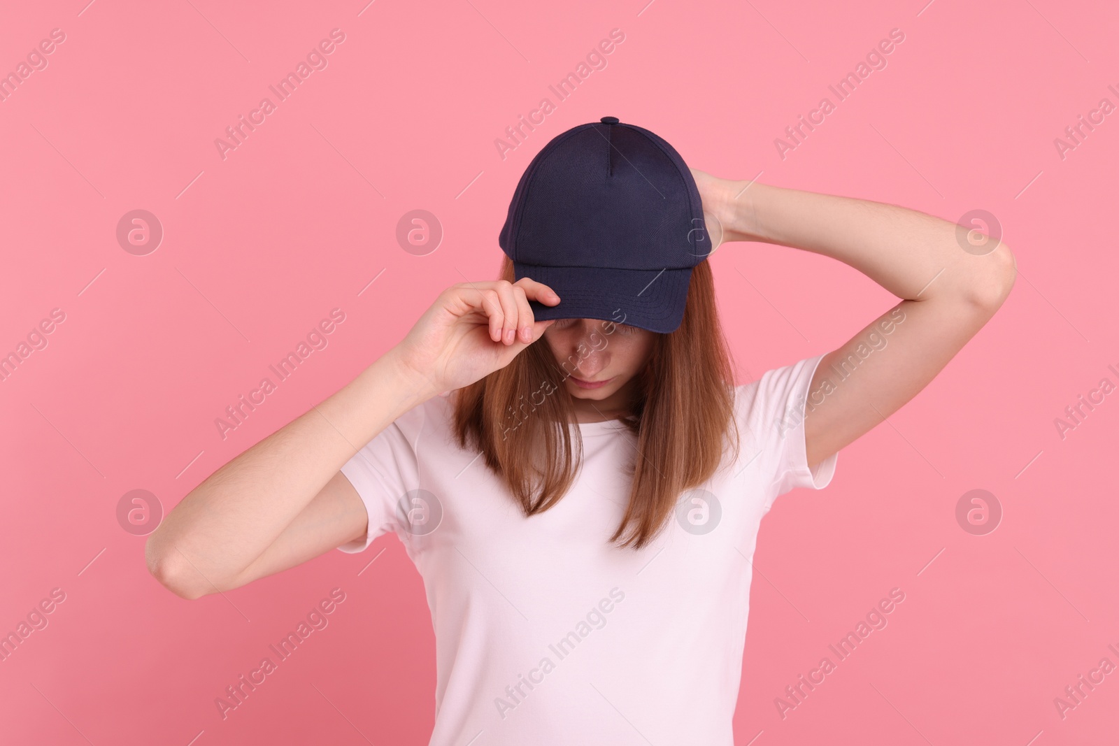 Photo of Woman in stylish baseball cap on pink background. Mockup for design