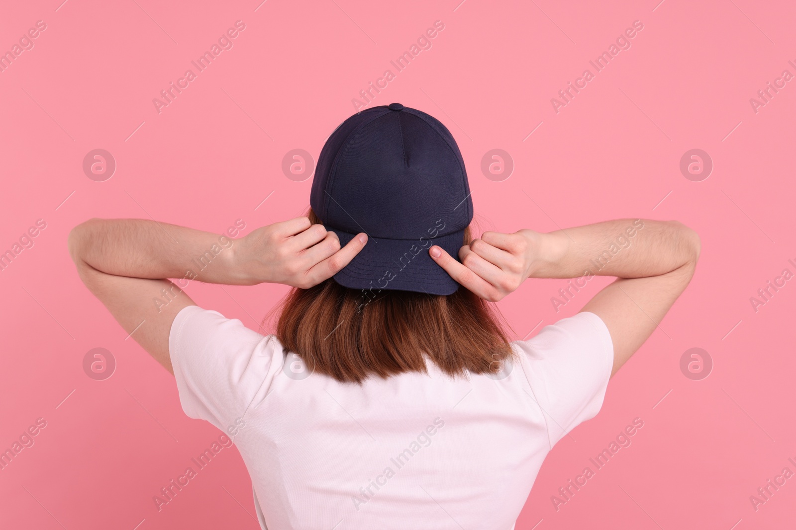 Photo of Woman in stylish baseball cap on pink background, back view. Mockup for design