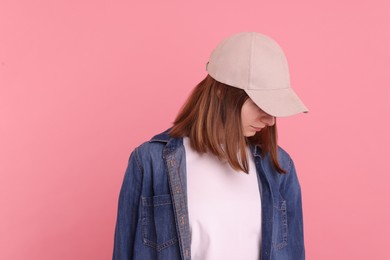 Woman in stylish baseball cap on pink background. Mockup for design