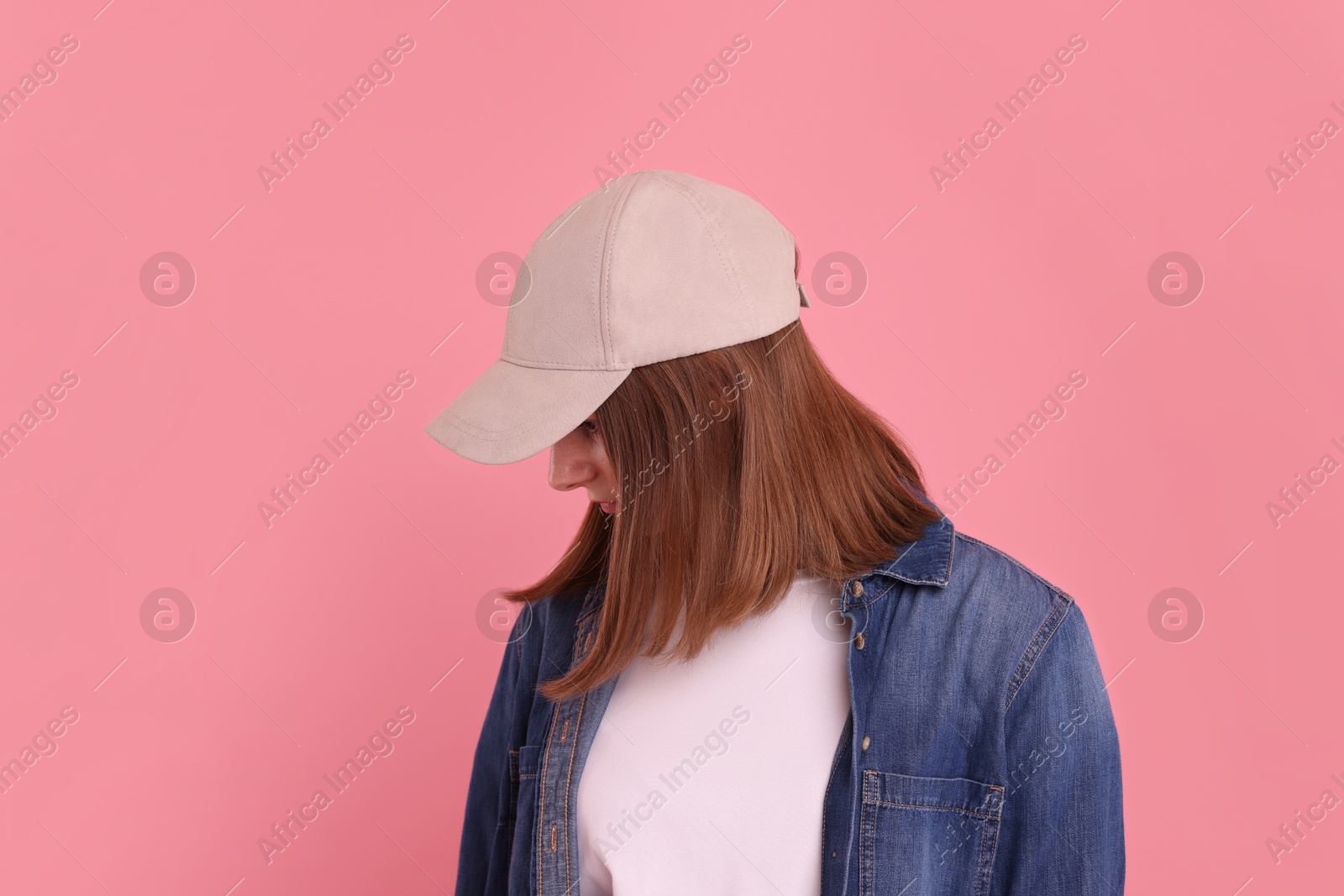 Photo of Woman in stylish baseball cap on pink background. Mockup for design