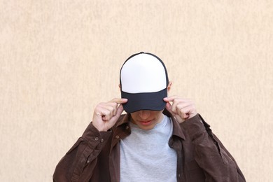 Photo of Man in stylish baseball cap near beige wall. Mockup for design