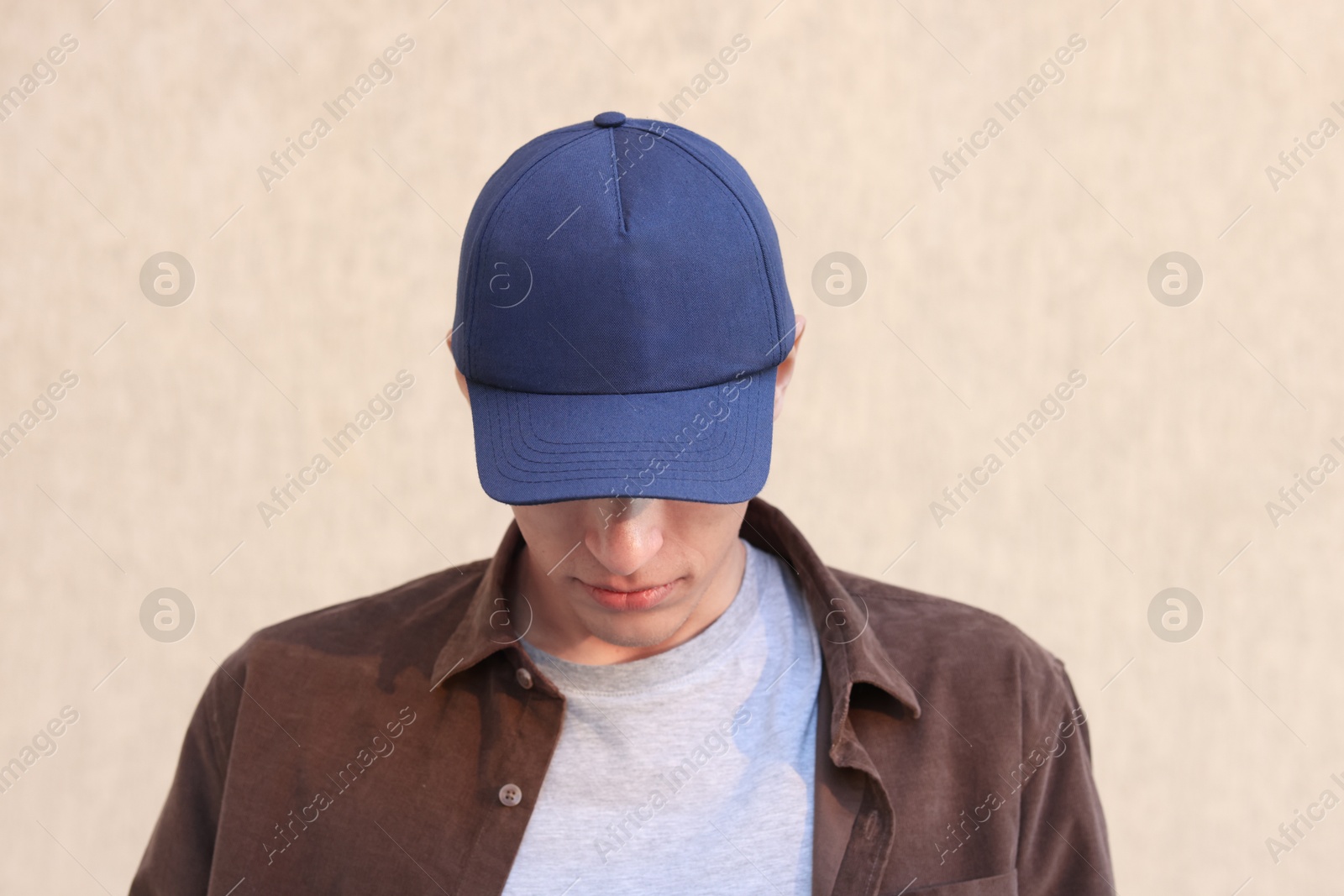 Photo of Man in stylish baseball cap near beige wall. Mockup for design