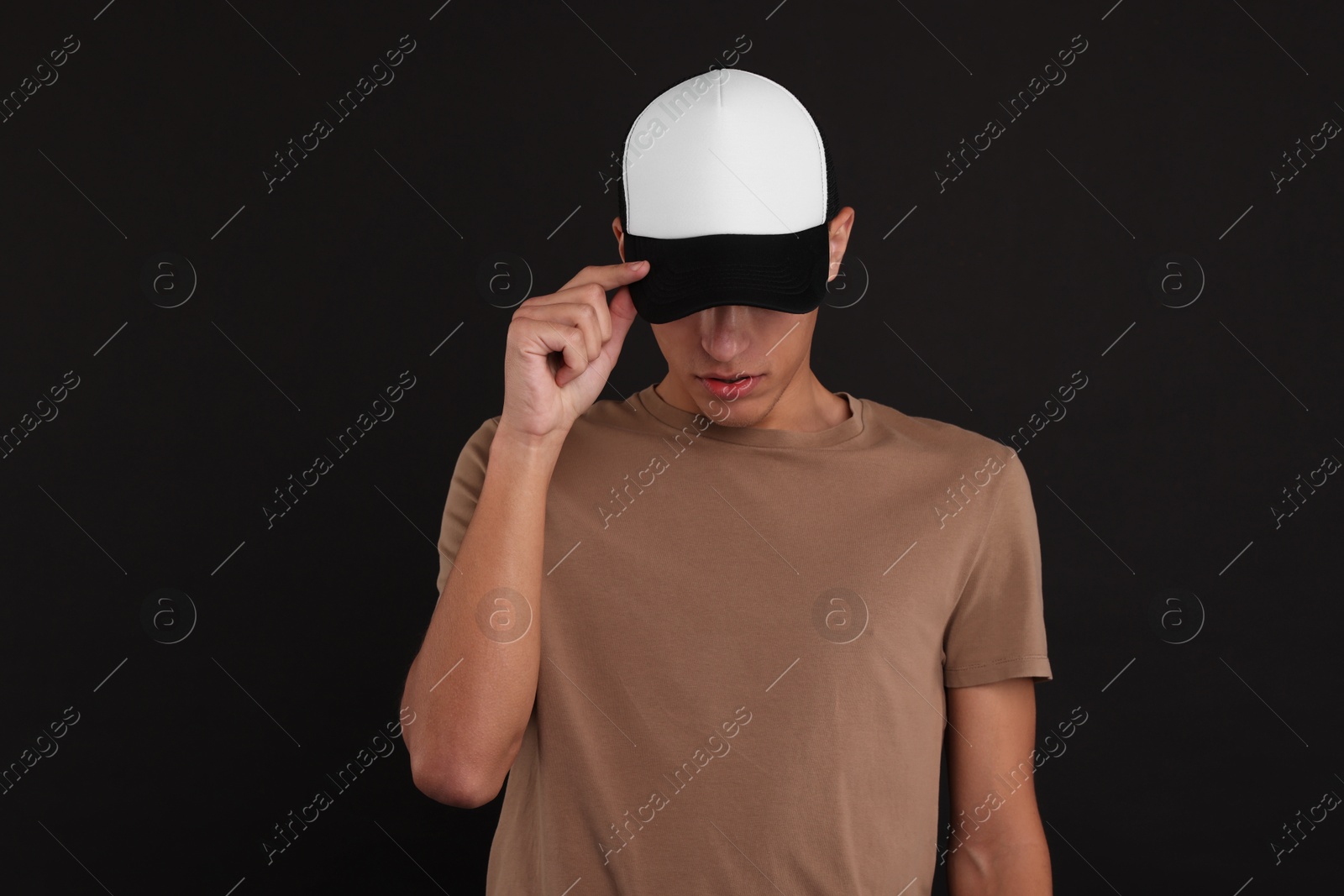 Photo of Man in stylish baseball cap on black background. Mockup for design