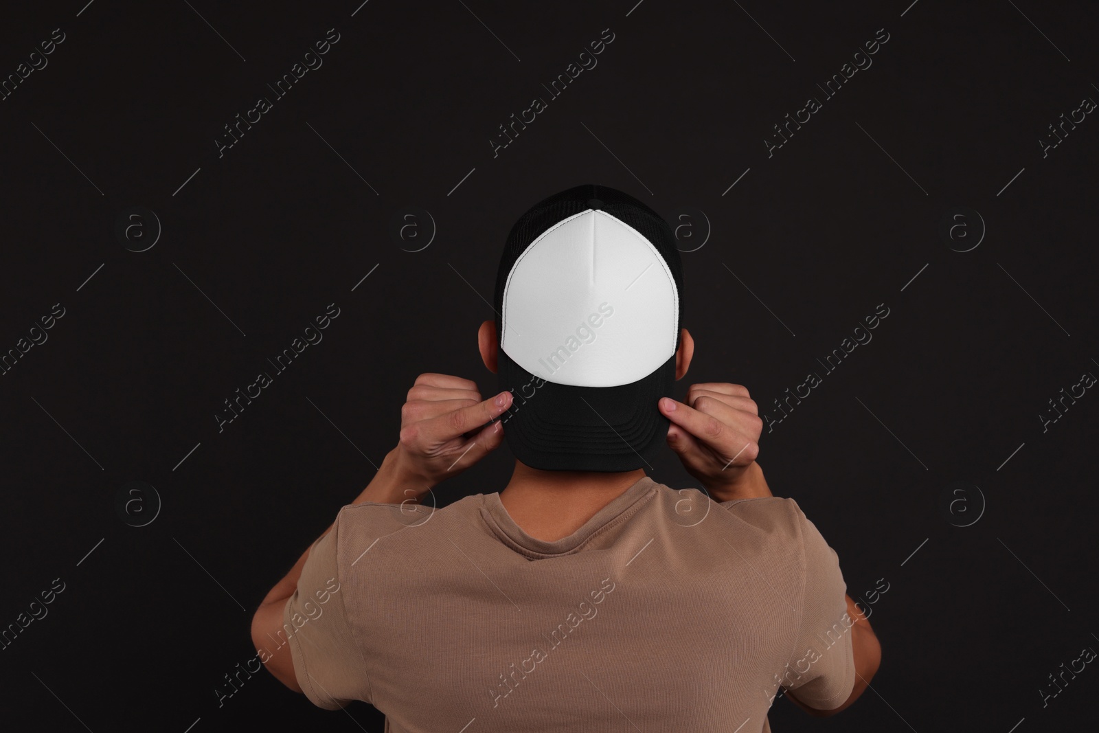 Photo of Man in stylish baseball cap on black background, back view. Mockup for design