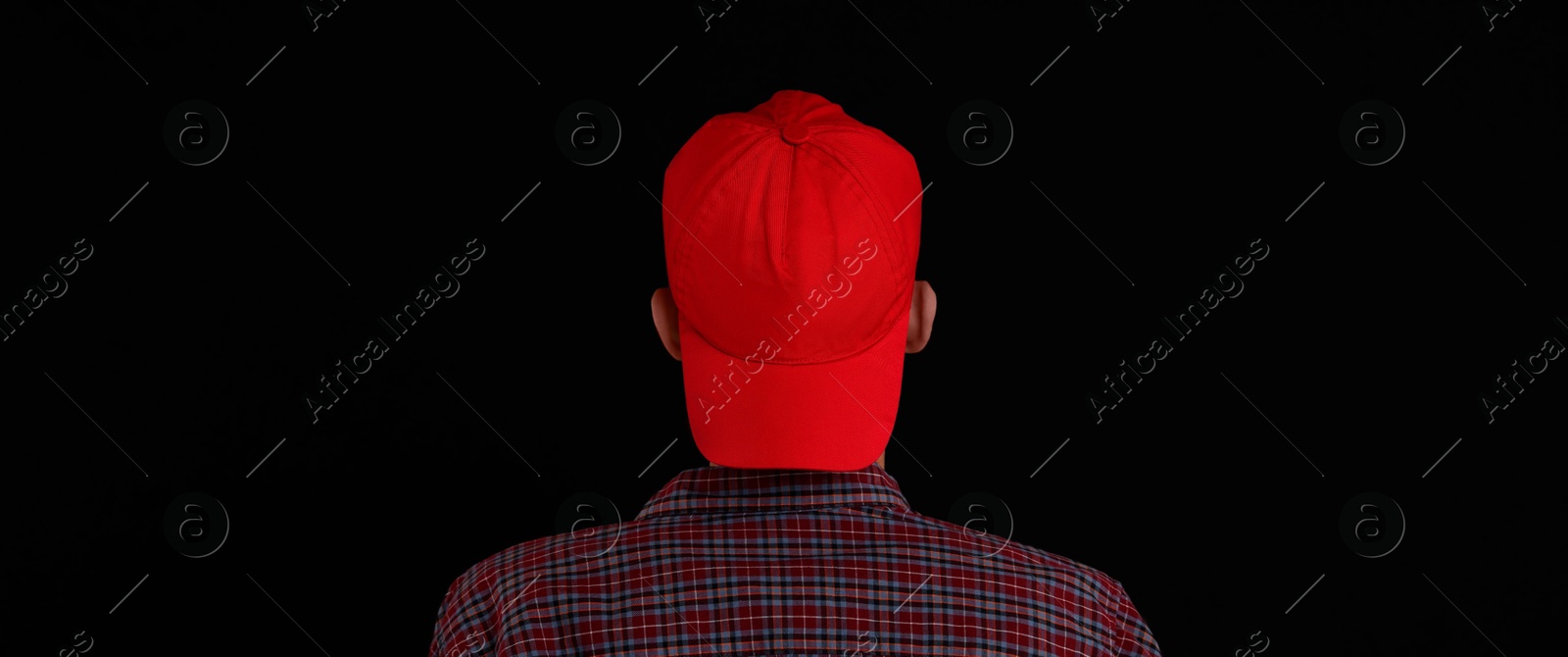 Photo of Man in stylish baseball cap on black background, back view. Mockup for design