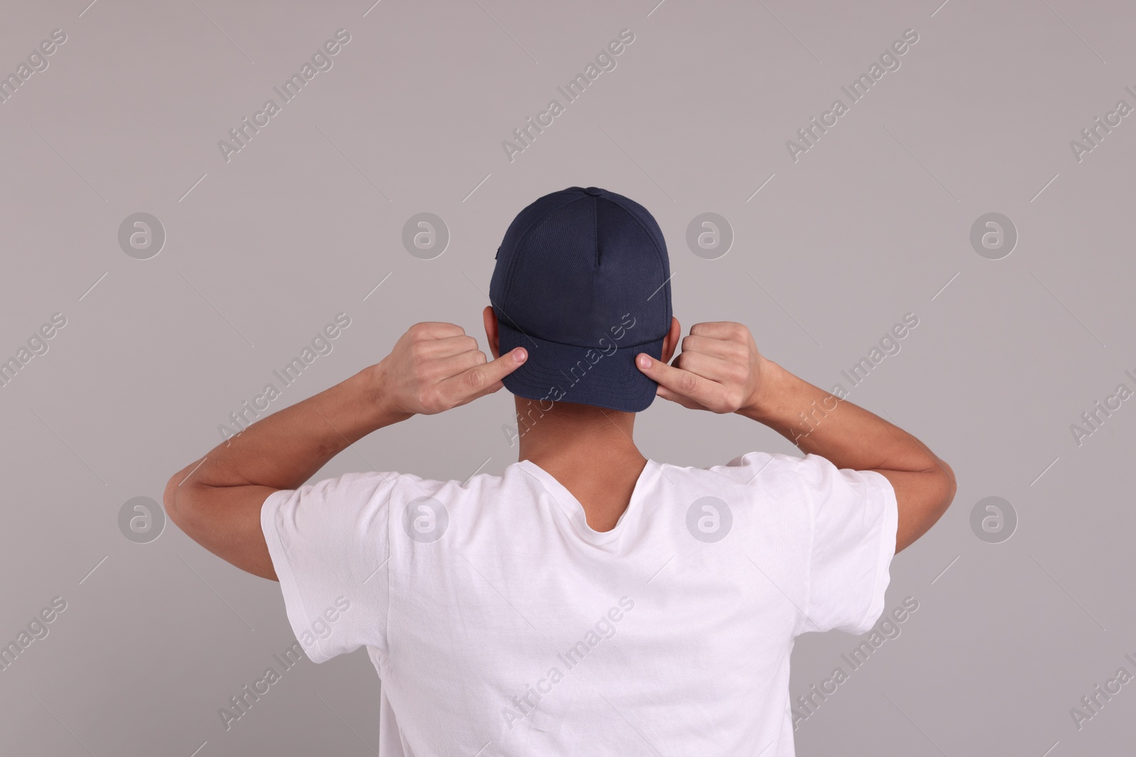 Photo of Man in stylish baseball cap on grey background, back view. Mockup for design