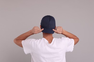 Photo of Man in stylish baseball cap on grey background, back view. Mockup for design