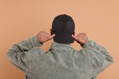 Photo of Man in stylish baseball cap on beige background, back view. Mockup for design