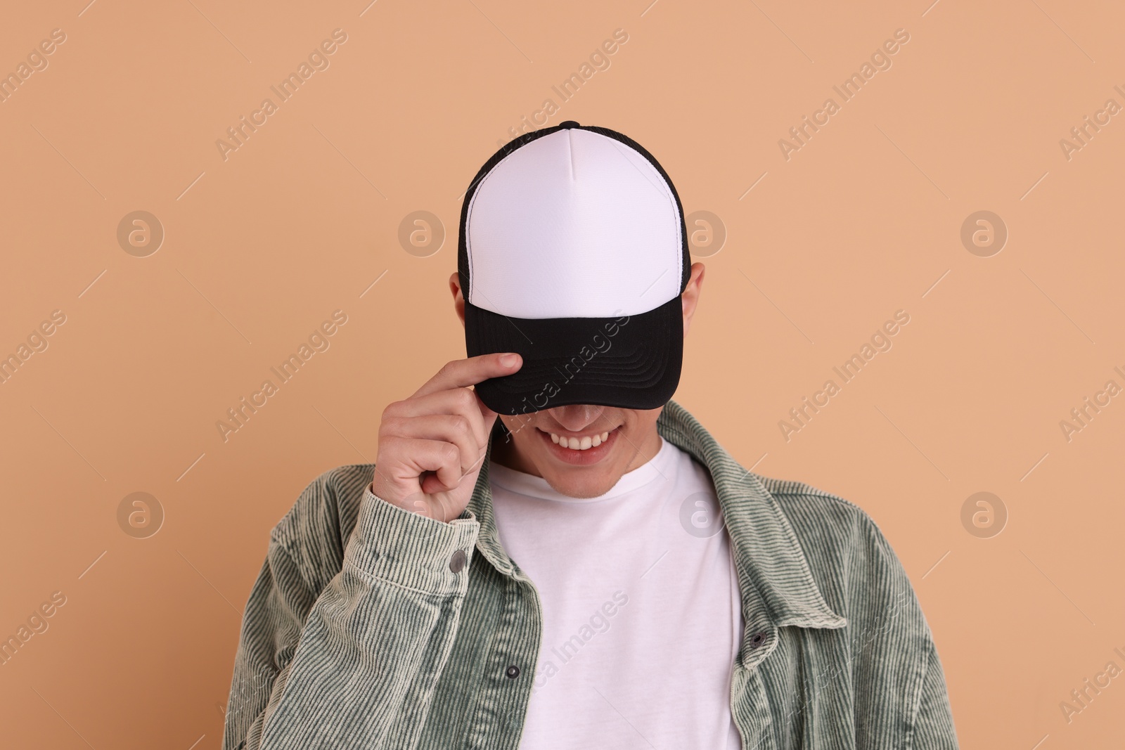 Photo of Smiling man in stylish baseball cap on beige background. Mockup for design